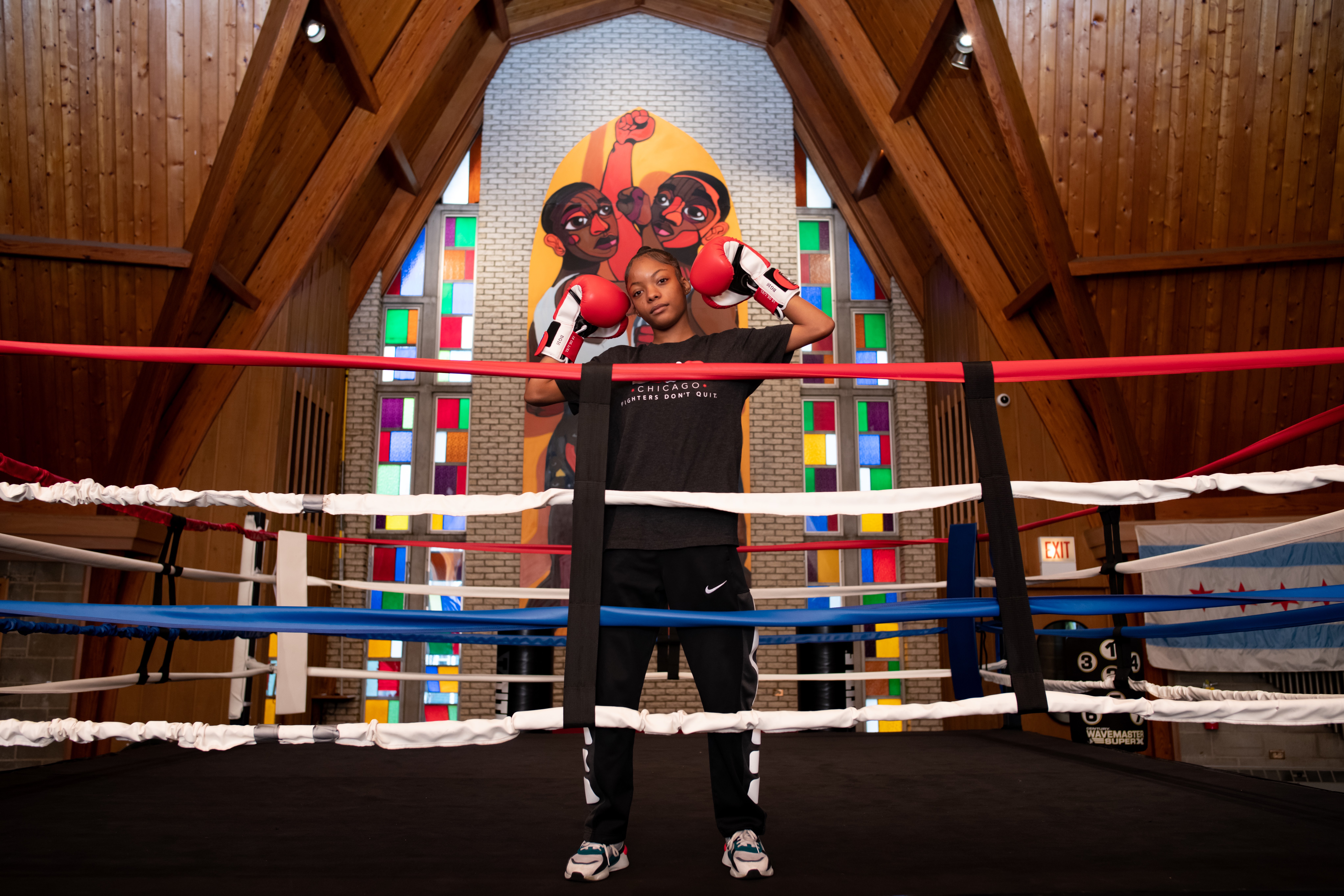 A young fighter stands in the ring with gloves raised