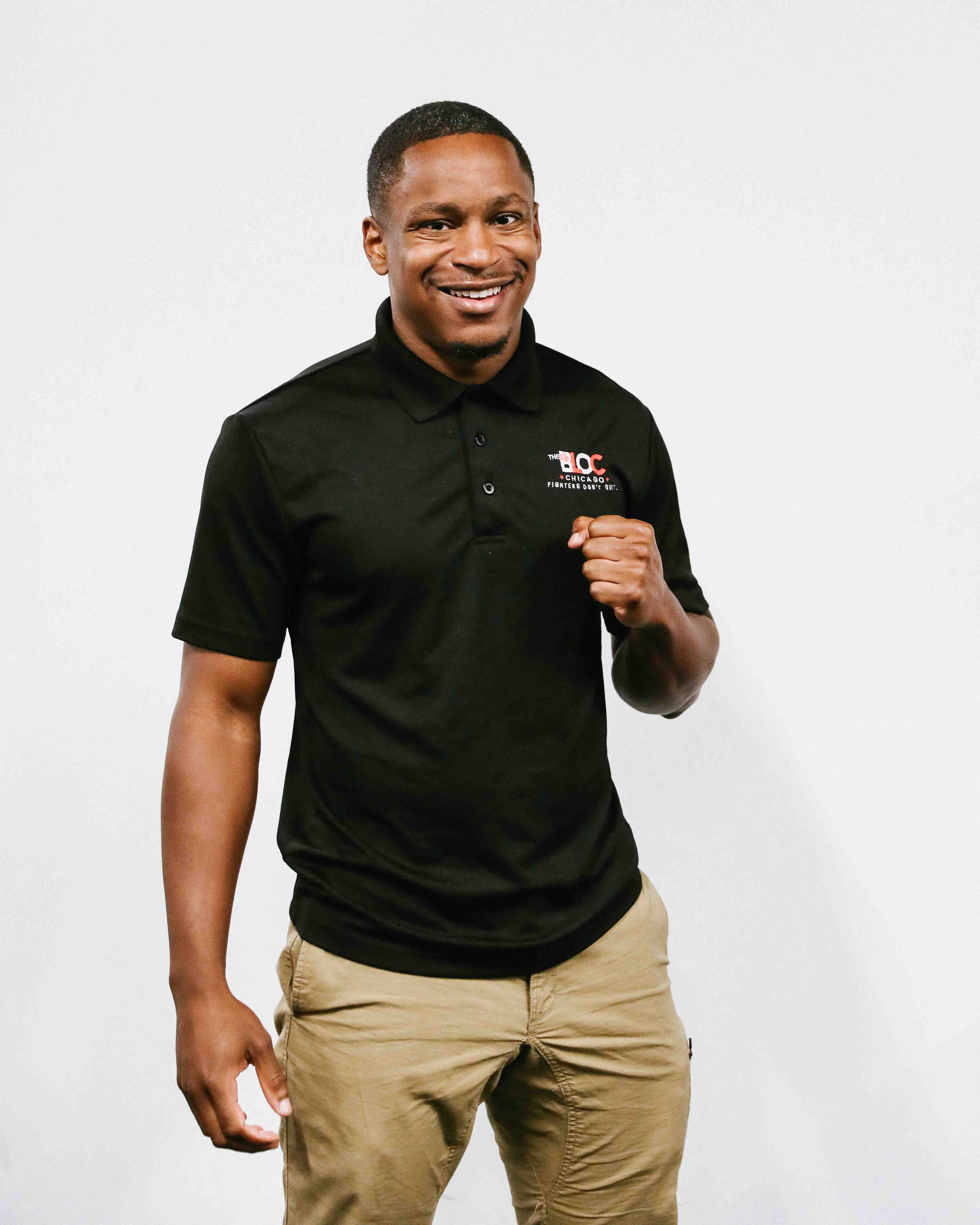 Jamyle Cannon studio portrait wearing The Bloc polo, smiling with hands clasped