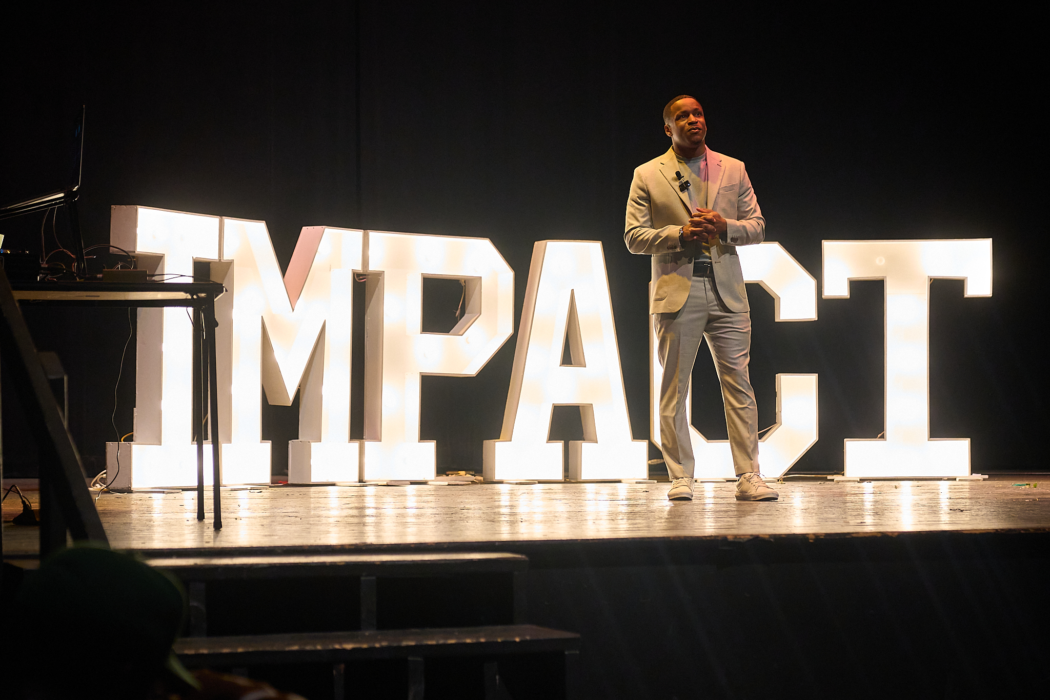 Jamyle Cannon standing in front of illuminated IMPACT letters